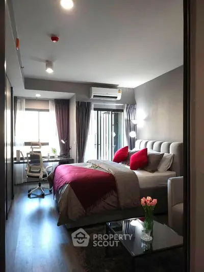 Modern bedroom with stylish decor and workspace, featuring a cozy bed and natural light.