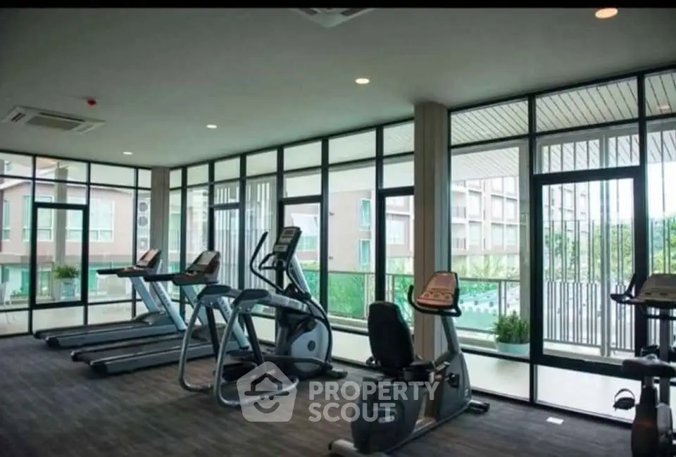 Spacious modern gym with large windows and exercise equipment in a luxury residential building.