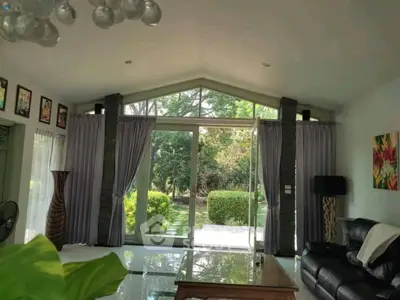Spacious living room with large windows overlooking a lush garden, elegant decor and natural light.