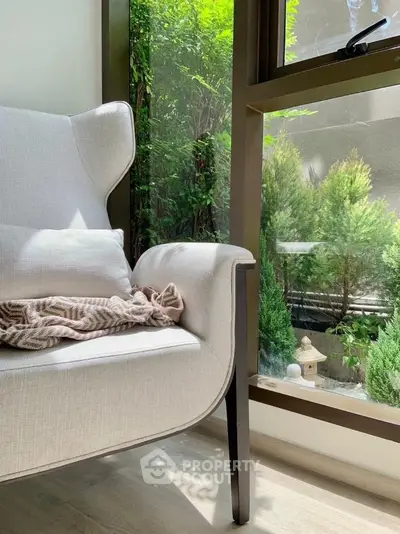 Cozy corner with elegant armchair and lush garden view through large window.