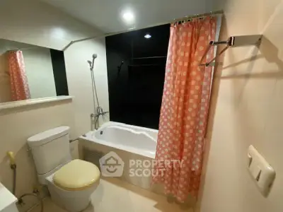 Modern bathroom with bathtub and polka dot shower curtain in cozy apartment.