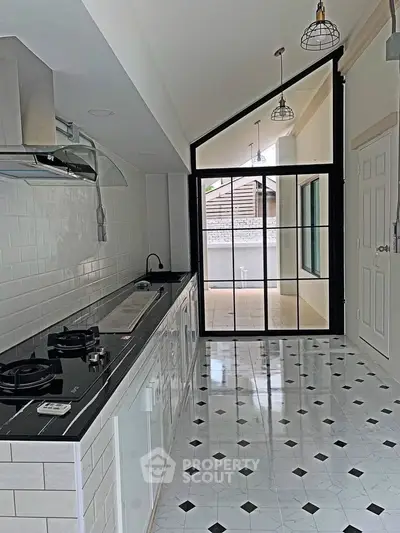 Sleek modern kitchen with glossy tiles and open layout, featuring gas stove and stylish lighting.