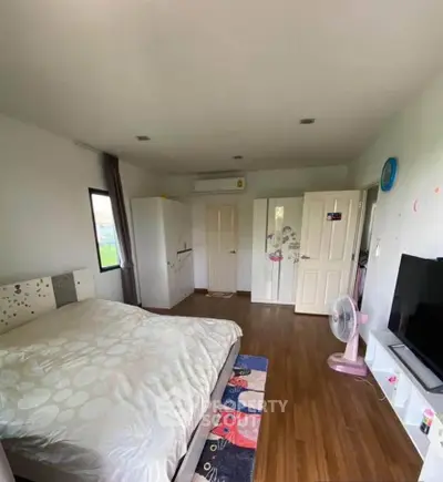 Spacious bedroom with modern decor and wooden flooring, featuring a large bed and a flat-screen TV.
