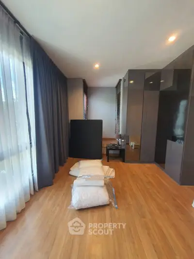Spacious modern bedroom with wooden flooring and large windows for natural light.