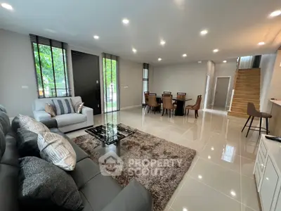 Spacious modern living room with elegant decor and dining area, featuring plush seating and stylish lighting.