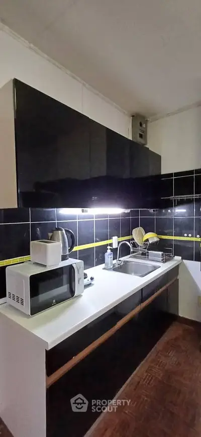 Modern kitchen with sleek black cabinets and microwave, featuring a clean and functional design.