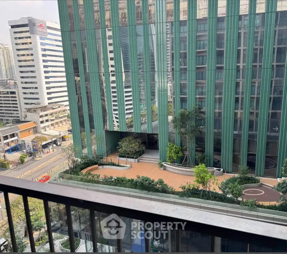 Stunning urban view from a high-rise balcony overlooking modern architecture and lush greenery.