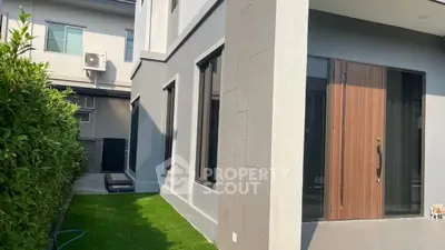 Modern home exterior with sleek design and lush greenery, featuring a stylish wooden door and manicured lawn.
