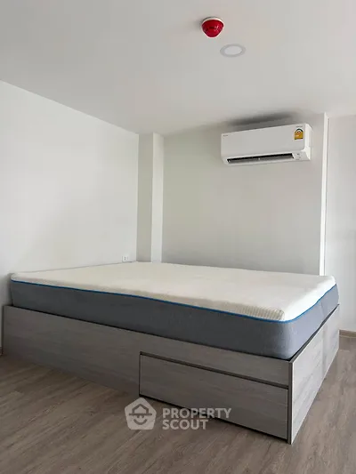 Modern bedroom with sleek bed frame and air conditioning unit, perfect for comfortable living.
