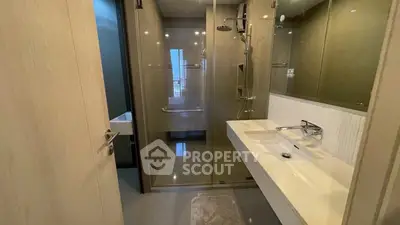Modern bathroom with glass shower and sleek vanity in contemporary apartment.