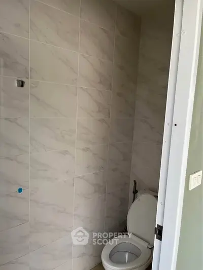 Modern bathroom with marble tiles and white toilet in a new property.