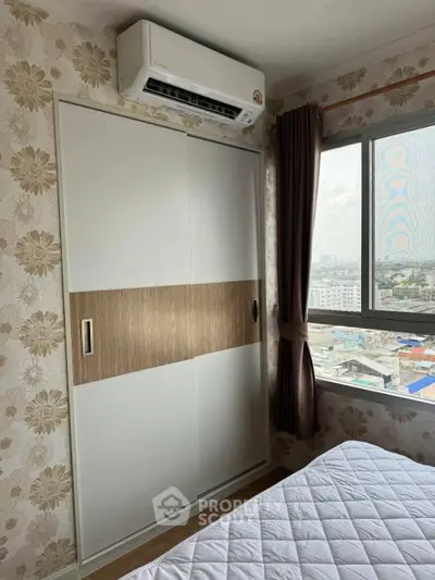 Cozy bedroom with floral wallpaper, large window, and air conditioning unit, offering a city view.