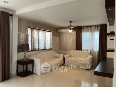Spacious living room with elegant decor and natural light, featuring cozy sofas and stylish shelving.
