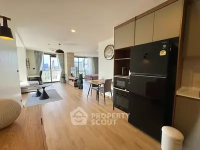 Spacious modern living room with open kitchen and city view, featuring sleek appliances and stylish decor.
