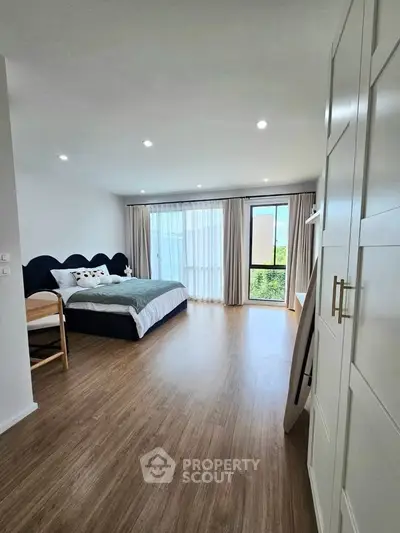 Spacious bedroom with modern decor and large window offering natural light and serene views.