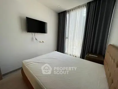 Modern bedroom with wall-mounted TV and large window with curtains