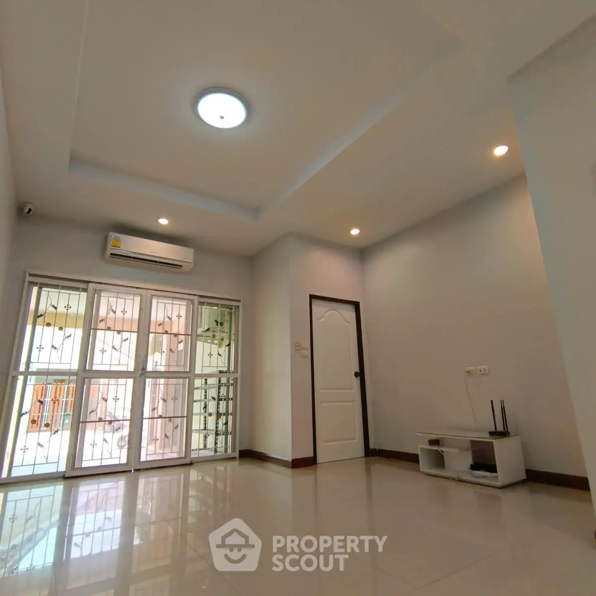 Spacious living room with modern lighting and air conditioning, featuring large windows for natural light.