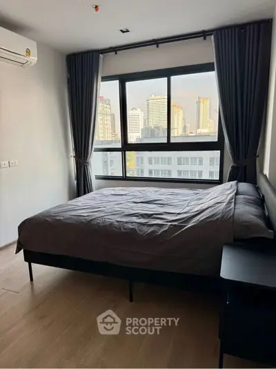 Modern bedroom with city view and large window, featuring stylish curtains and sleek design.
