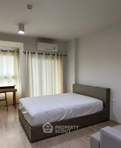 Modern bedroom with minimalist design, featuring a comfortable bed and natural light from large windows.