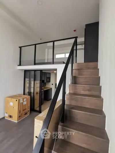 Modern loft apartment with sleek staircase and glass railing, featuring a spacious open layout and high ceilings.
