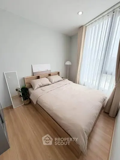 Cozy bedroom with large window and modern decor, perfect for relaxation and comfort.