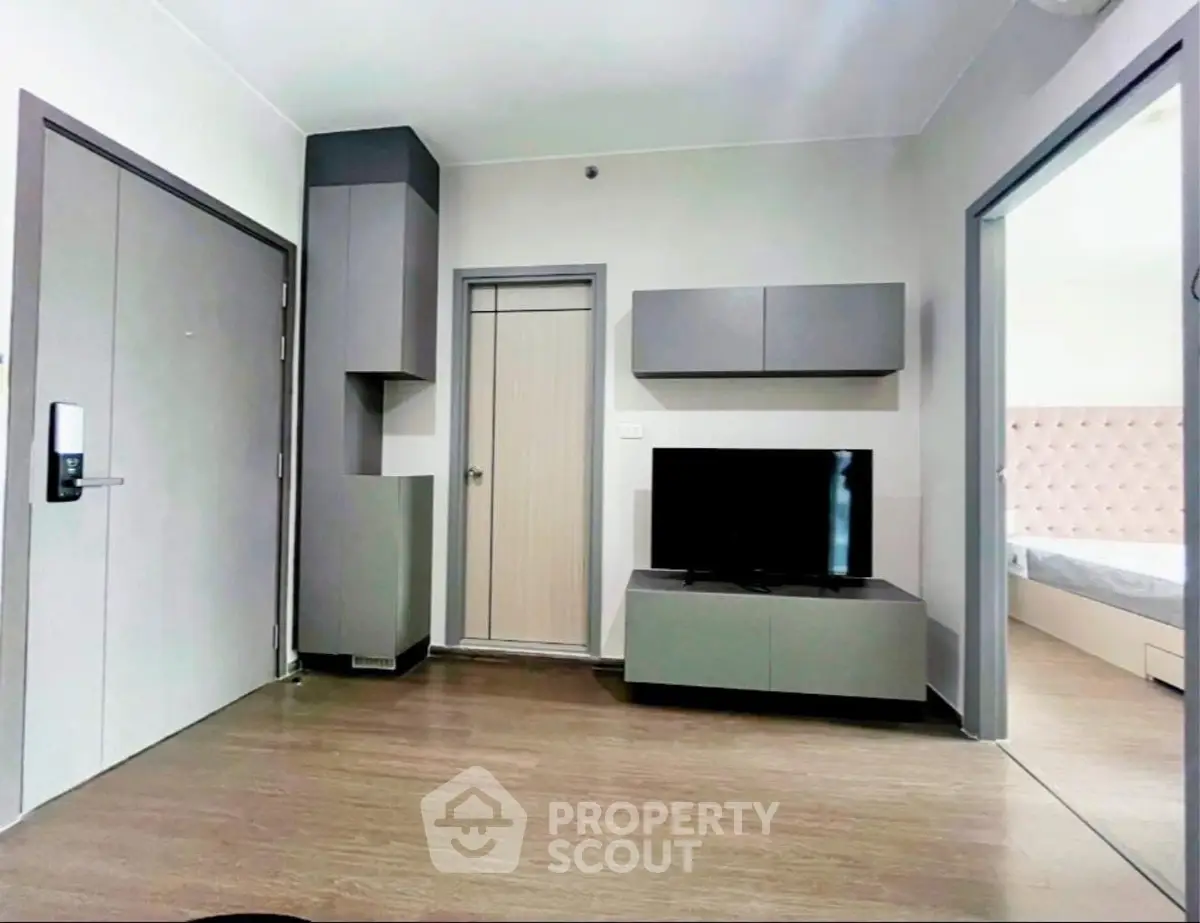 Modern living room with sleek furniture and TV, adjacent to a stylish bedroom.