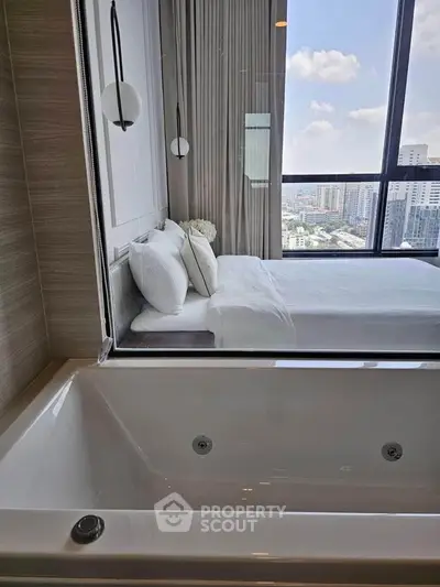 Luxurious bedroom with city view and modern bathtub in high-rise apartment.