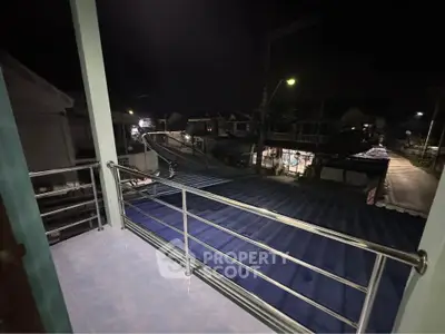 Cozy balcony with night view of neighborhood rooftops and street lights.