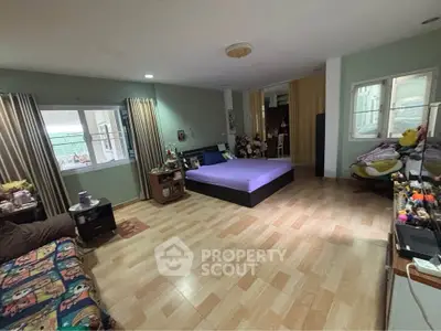 Spacious bedroom with modern decor and ample natural light, featuring a cozy bed and stylish furnishings.