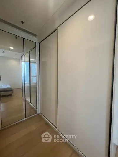 Modern bedroom with sleek mirrored wardrobe and wooden flooring
