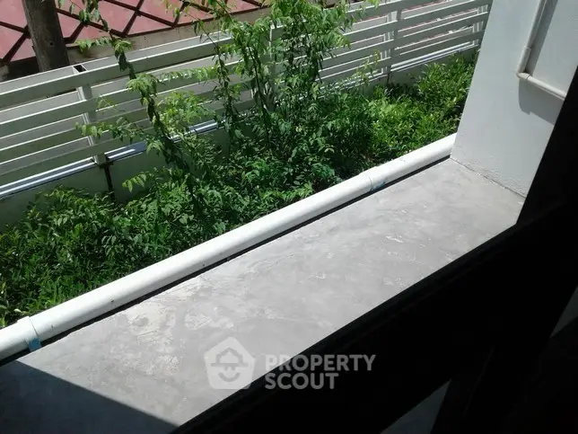 Modern balcony view with lush greenery and sleek design.