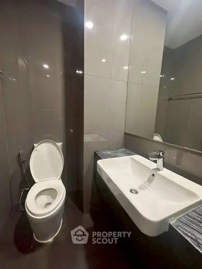 Modern bathroom with sleek fixtures and large mirror in contemporary apartment.