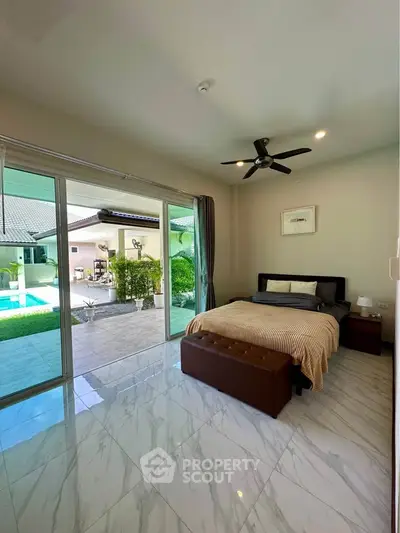 Spacious bedroom with pool view and sliding glass doors in modern home