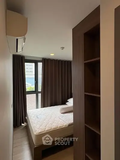 Cozy bedroom with large window and modern furnishings in a stylish apartment.