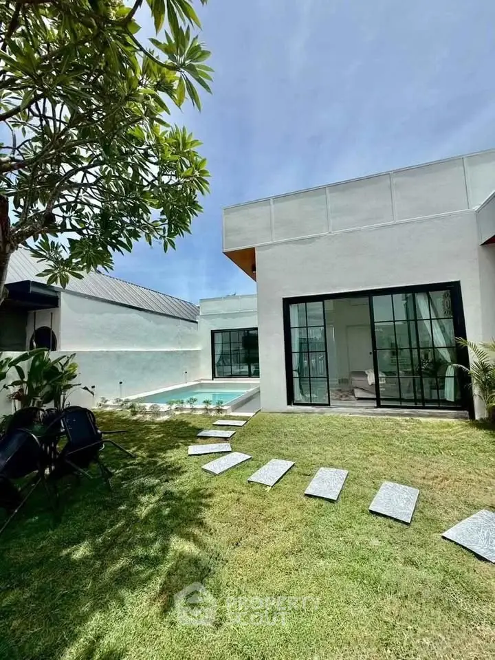 Modern home with pool and lush garden, featuring sleek glass doors and a serene outdoor space.