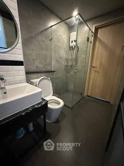 Modern bathroom with glass shower and sleek fixtures in contemporary apartment.