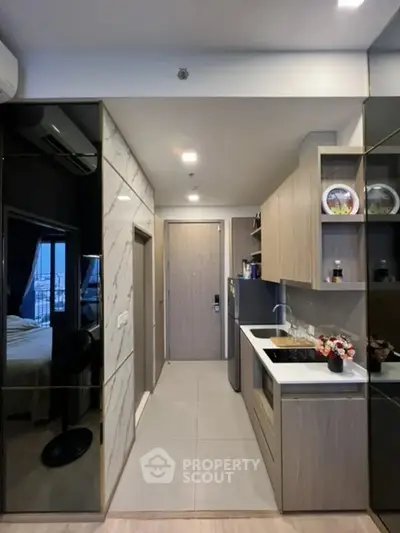 Modern compact kitchen with sleek cabinetry and integrated appliances in a stylish apartment.