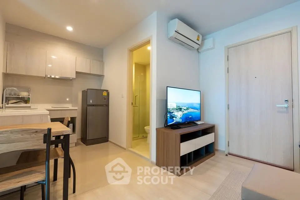 Modern apartment interior with open kitchen and cozy living area, featuring sleek appliances.