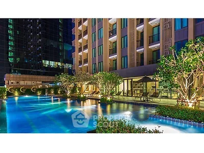 Luxurious apartment complex with stunning illuminated pool and lush greenery at night.