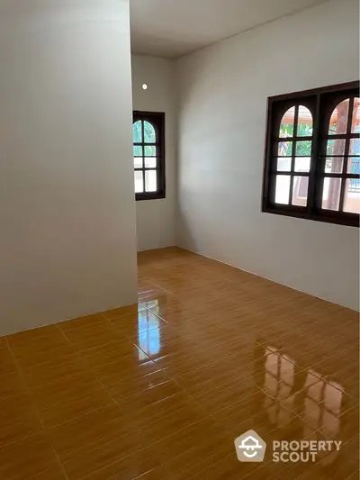 Spacious and bright unfurnished living room with polished terracotta tiles and charming arched windows inviting ample natural light.