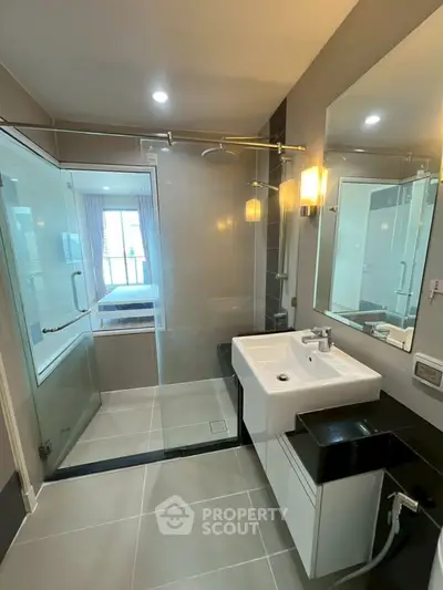 Modern bathroom with glass shower and sleek fixtures in a contemporary apartment.
