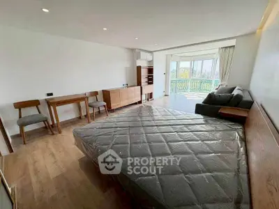 Spacious bedroom with modern furniture and large windows offering natural light and a view.