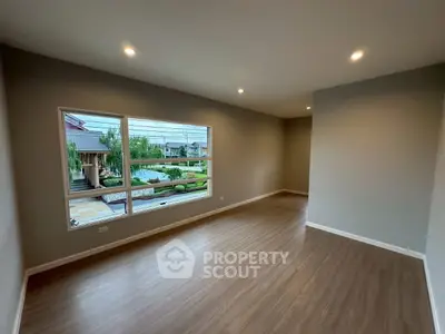 Spacious empty room with large window and garden view, perfect for customization.