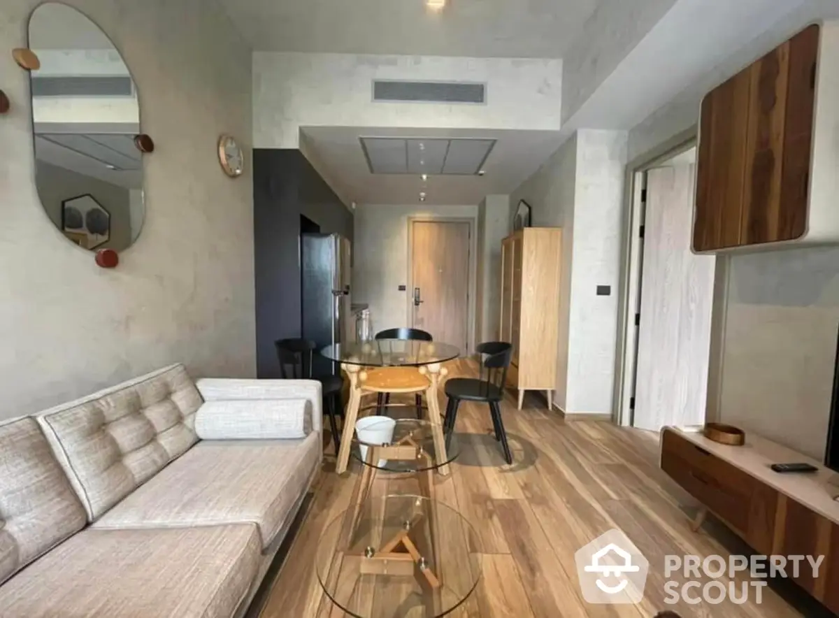 Modern living room with elegant wooden flooring, cozy beige sofa, and a stylish glass-top dining table, perfect for urban living.