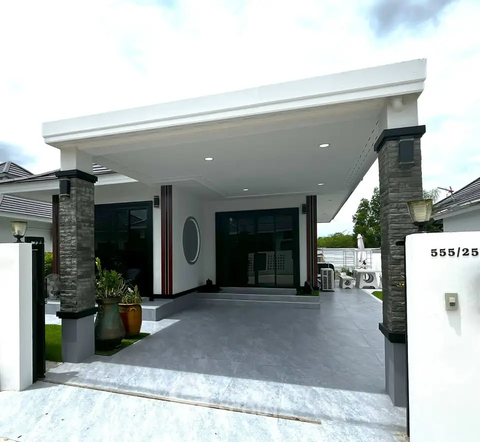 Modern single-story house with spacious carport and elegant stone pillars.