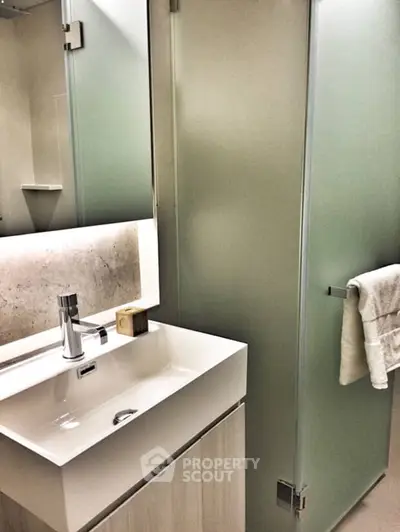 Modern bathroom with sleek sink and frosted glass shower door.