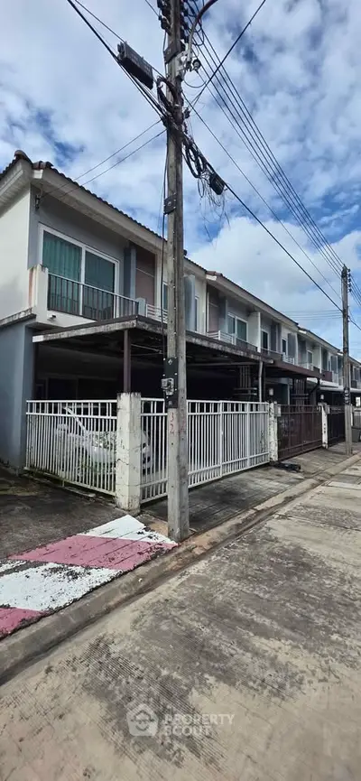 Modern townhouse exterior with gated parking and clear blue sky.