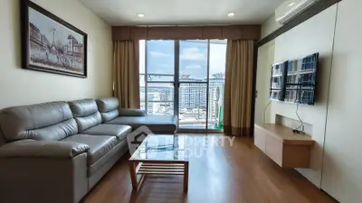 Spacious living room with modern decor and city view, featuring a comfortable sofa and wall-mounted TV.