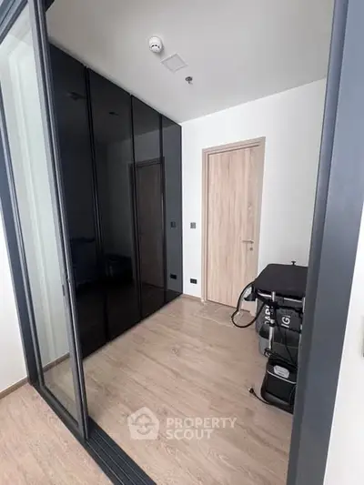 Modern hallway with sleek black wardrobe and wooden flooring in contemporary apartment.
