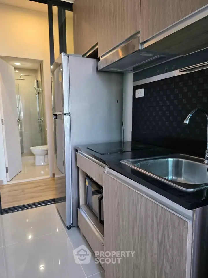 Modern compact kitchen with sleek cabinetry and stainless steel appliances in a stylish apartment.